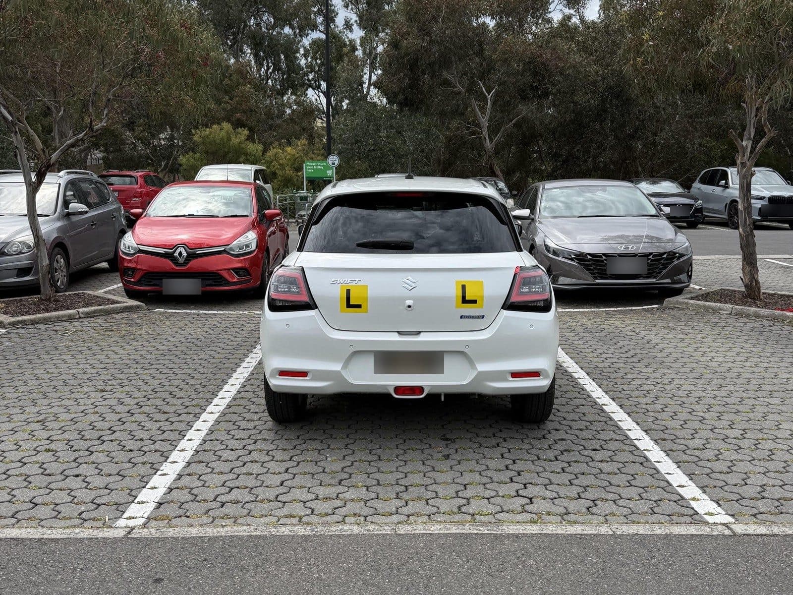 Stacey's Suzuki Swift parked straight in a marked bay at a shopping-centre carpark