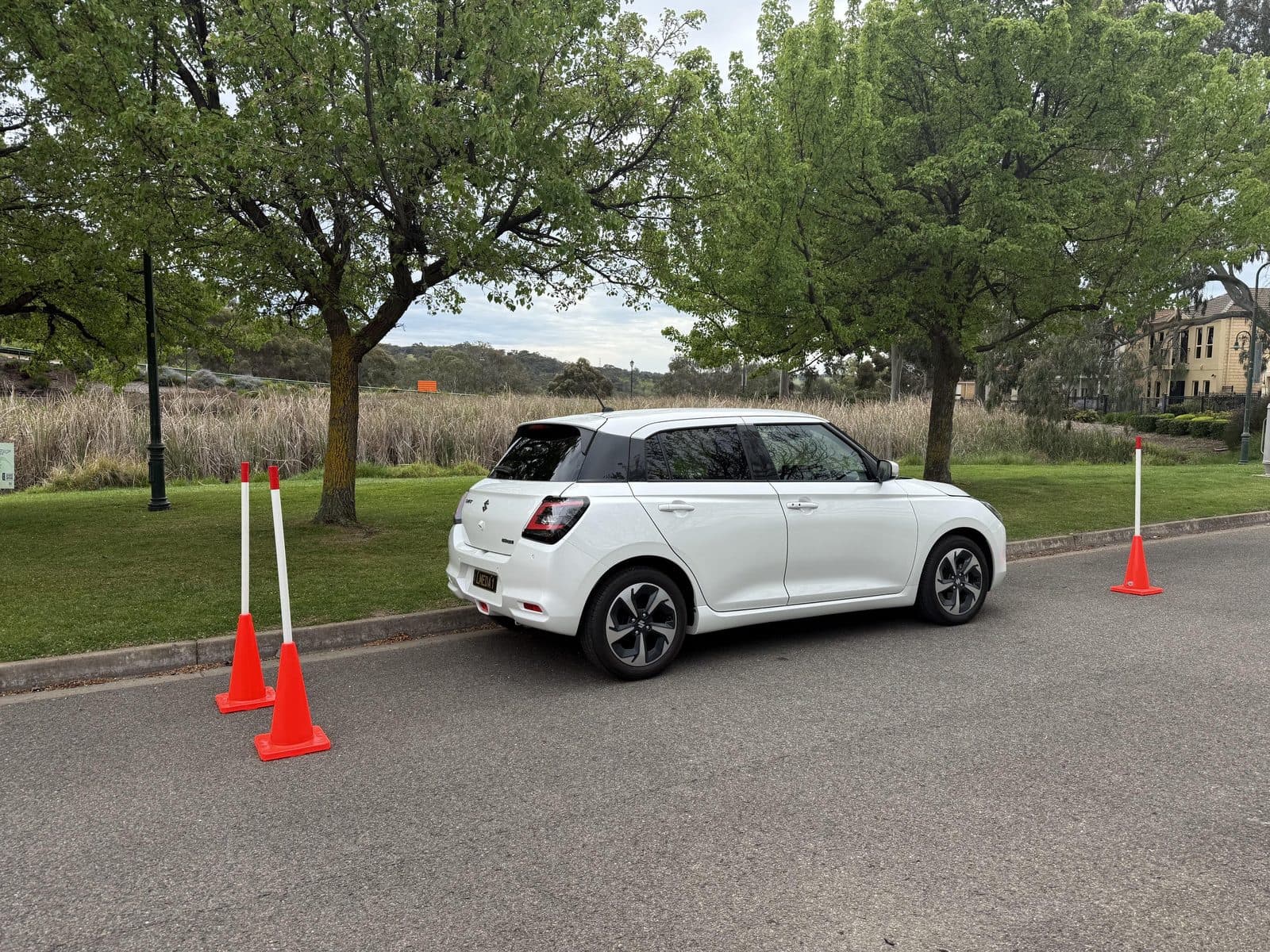 Stacey's white Suzuki Swift parked between witches' hats beside a park